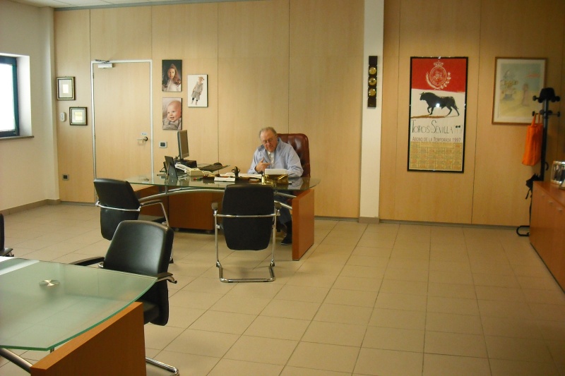 Ufficio della presidenza con scrivania in vetro, sedie nere e quadri alle pareti
