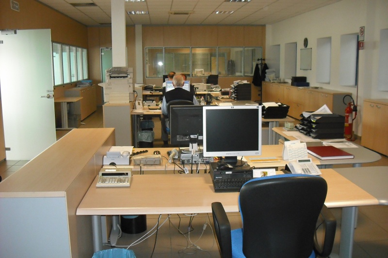 Ufficio diffusione con scrivanie, computer e telefoni, e un impiegato al lavoro