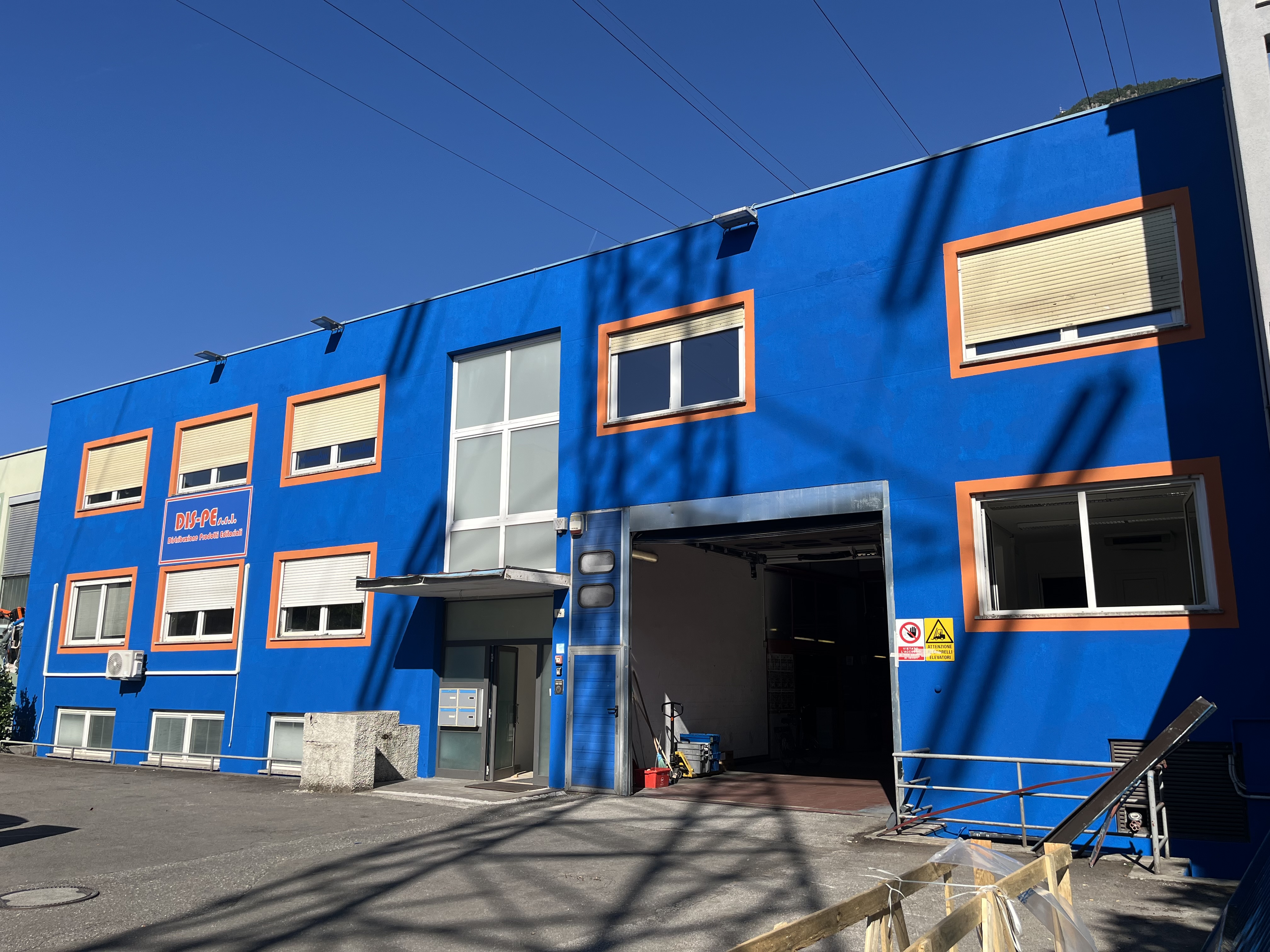 Sede di Bolzano: edificio blu con finestre arancioni e l'ingresso del magazzino